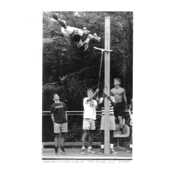 Black and white photo of a skater jumping with people watching.