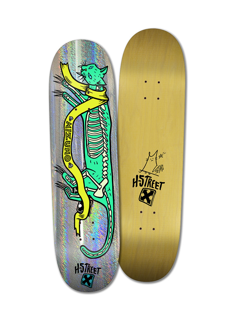 Two skateboard decks: Woodchuck’s THE MIZUHO HIDDEN CAT deck features a green skeleton cat with a yellow banner on holographic foil; the other is gold with black H-Street Alpha Girls branding and a stick figure sketch.