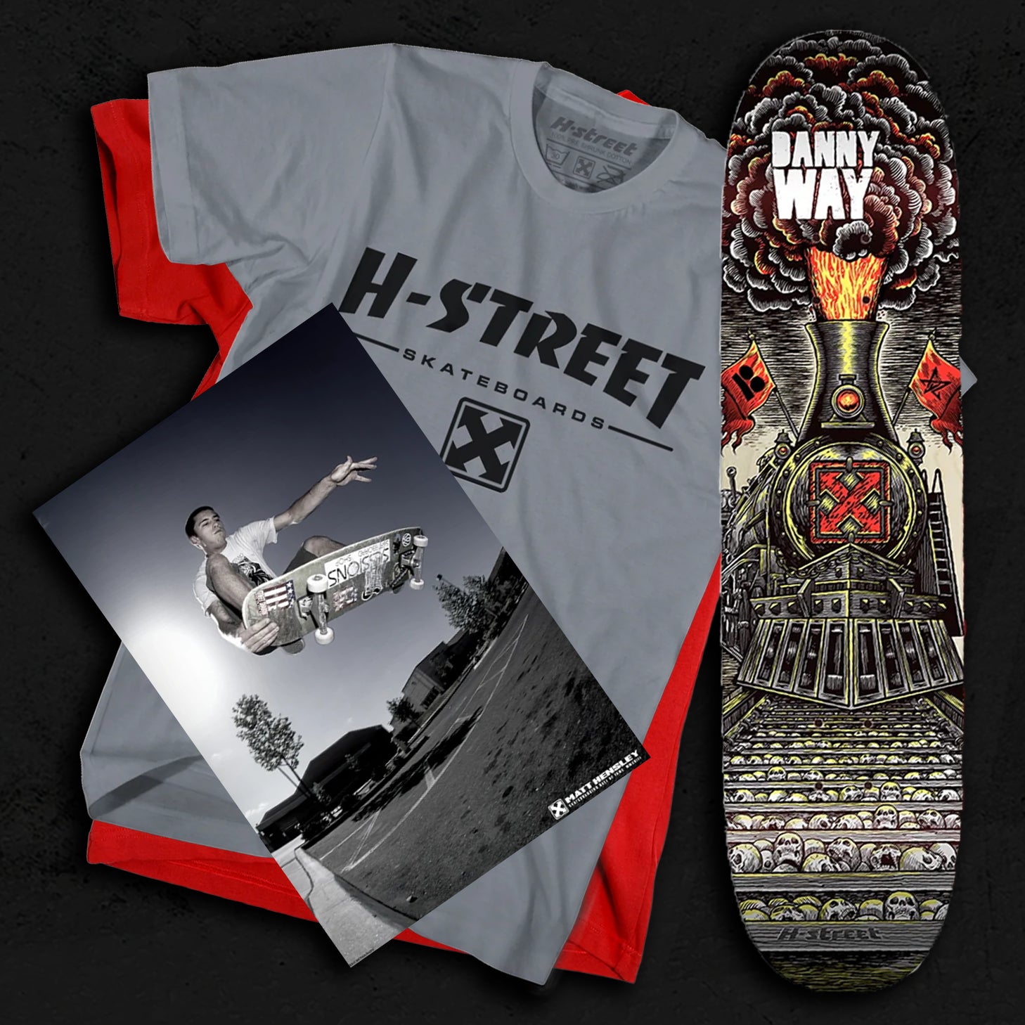 A grey shirt on top of a red shirt with a skateboard deck and a poster on a textured dark grey background.
