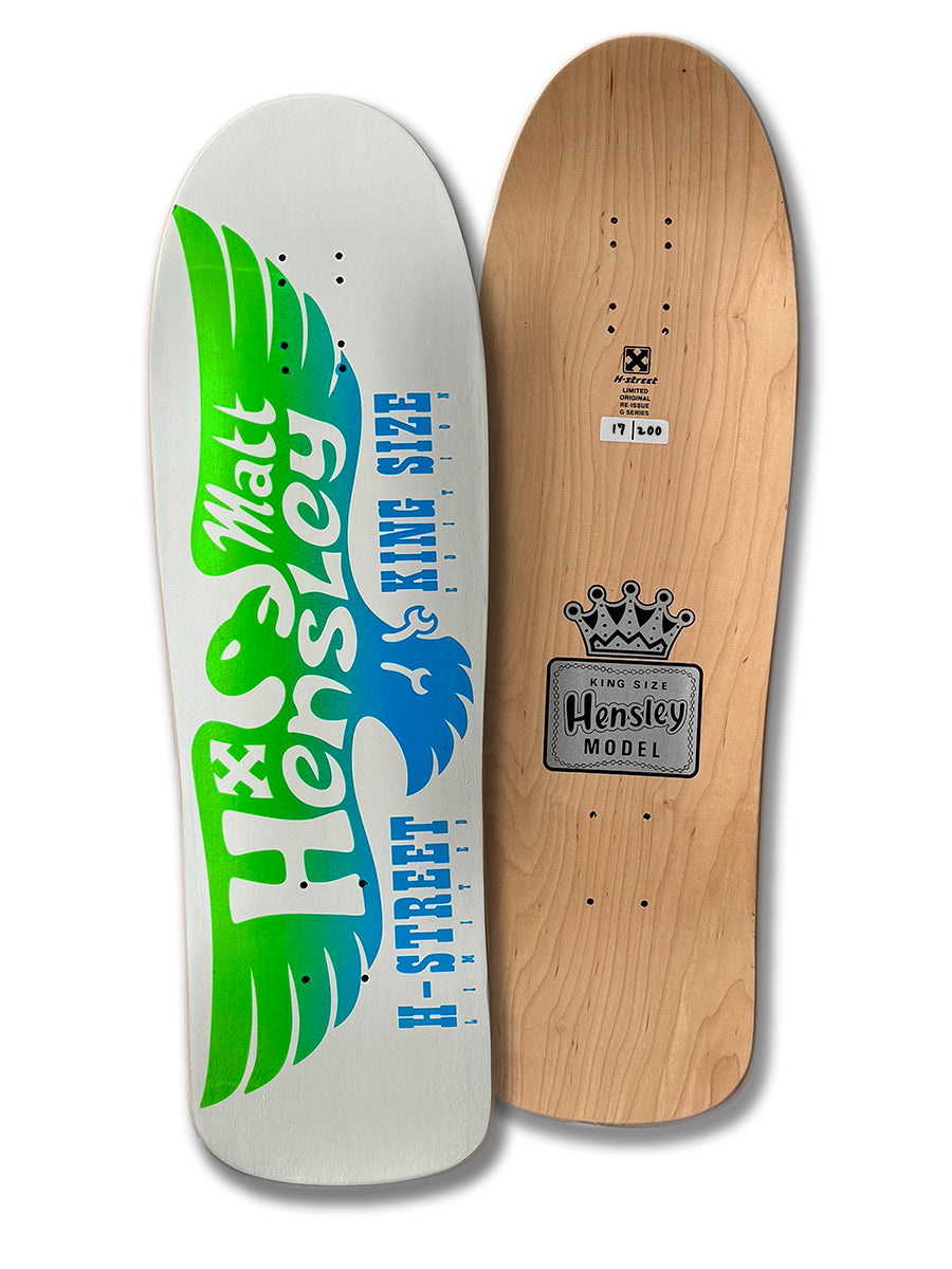 Two Legend Skates decks stand upright: left, the MATT HENSLEY KINGSIZE LE EAGLE, G SERIES with bold green and blue graphics; right, a natural wood finish with crown, "Hensley Model" label, Old School holes, and is numbered 17/100.