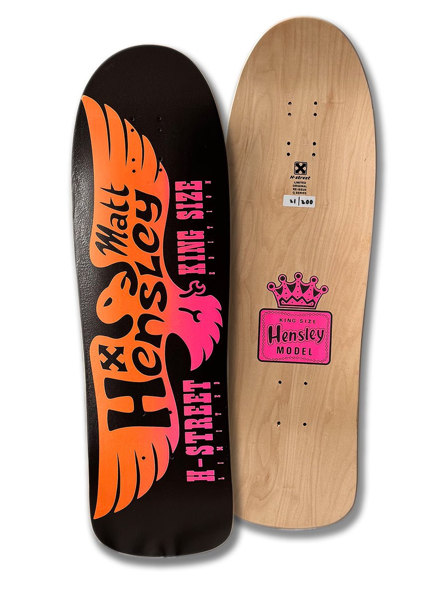Two handmade Legend Skates boards: the MATT HENSLEY KINGSIZE LE EAGLE, G SERIES with a black background and orange/pink winged text, and another with a natural wood finish, pink crown logo, "Hensley Model," and Old School hole pattern.