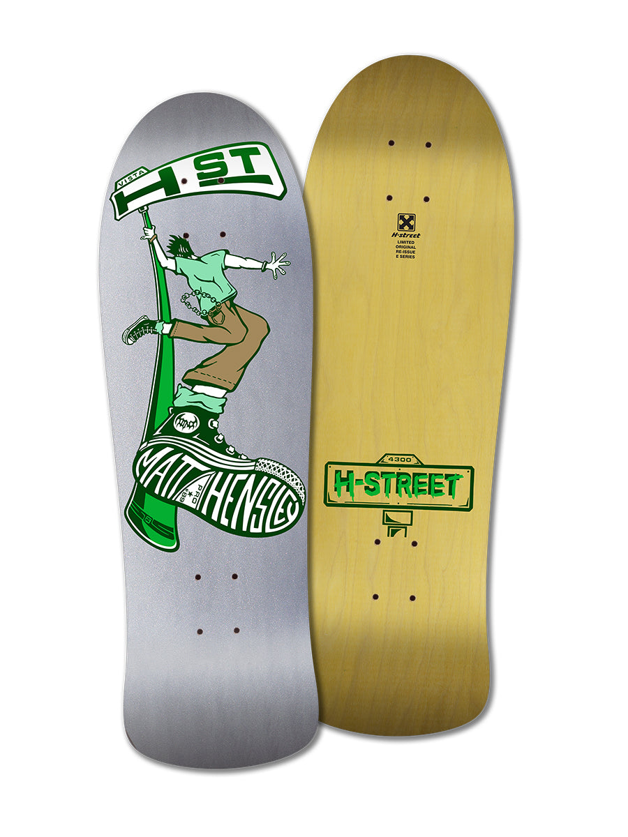 Two skateboard decks from Legend Skates’ MATT HENSLEY STREET SWINGER E SERIES: one has a green cartoon figure pole-jamming an H-Street sign above Matt Hensley, and the other features a plain wood back with a small green H-Street logo.