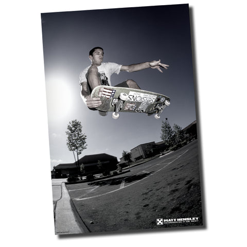 A black and white poster featuring a photograph of a person skateboarding in the air with a skateboard. The background shows a street scene with trees and a building.