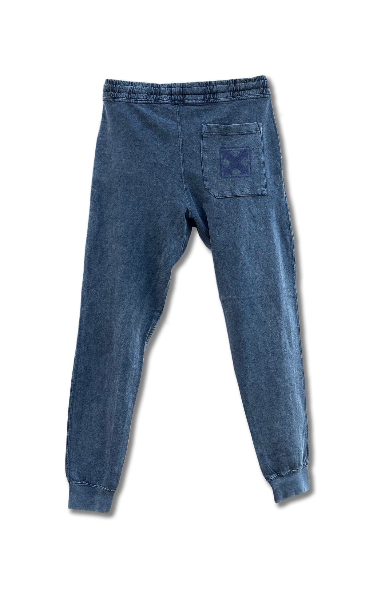 MH Printing MARK LOGO VINTAGE WASH SWEATPANTS: Blue unisex fleece joggers with elastic waistband and cuffs. Features a right back pocket with a dark blue stitched X, showcasing vintage style. Displayed flat on a white background.