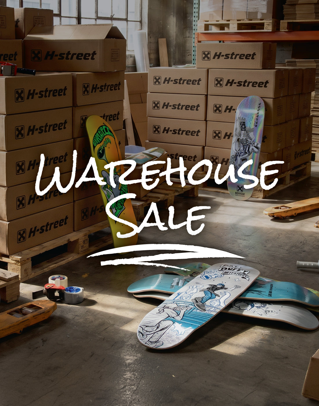 An image of a warehouse filled but H-Street labeled boxes and skateboard decks scattered around with the words 'Warehouse Sale' on top.