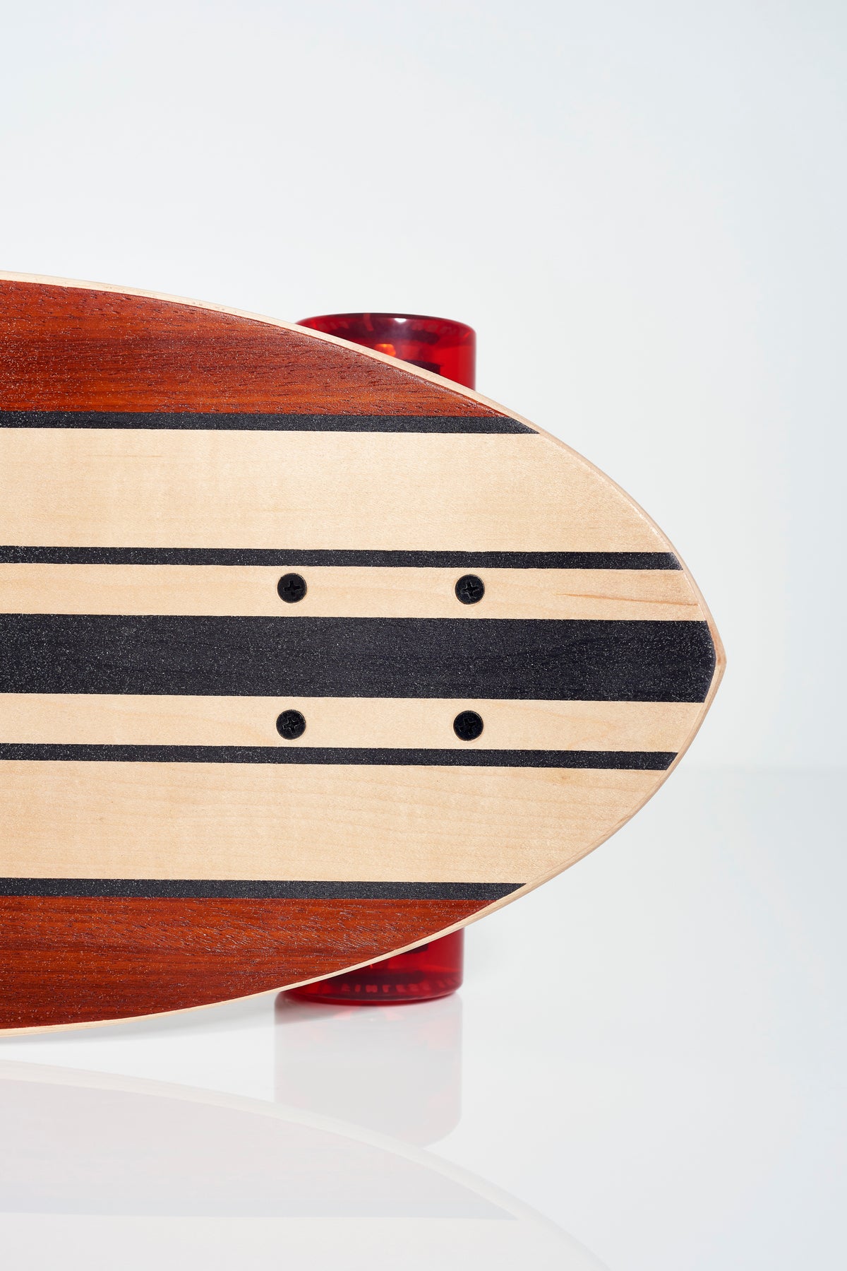 Close-up of the FINLESS COMPLETE longboard by Finless, featuring black stripes and visible mounting holes above a large red wheel, set against a white background.