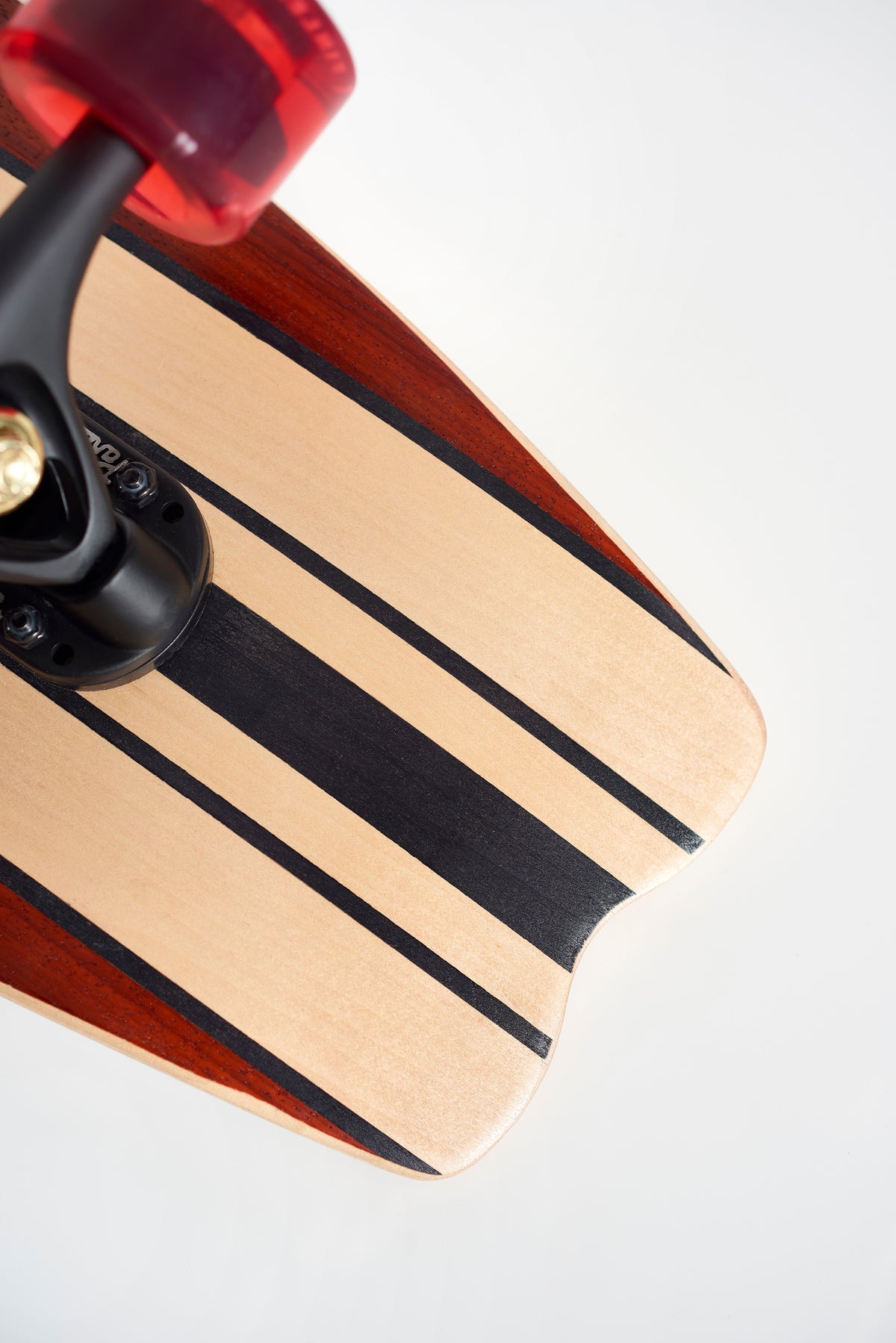 Close-up of the back end of the Finless FINLESS COMPLETE retro surf skateboard with black stripes and a red wheel, photographed against a plain white background.