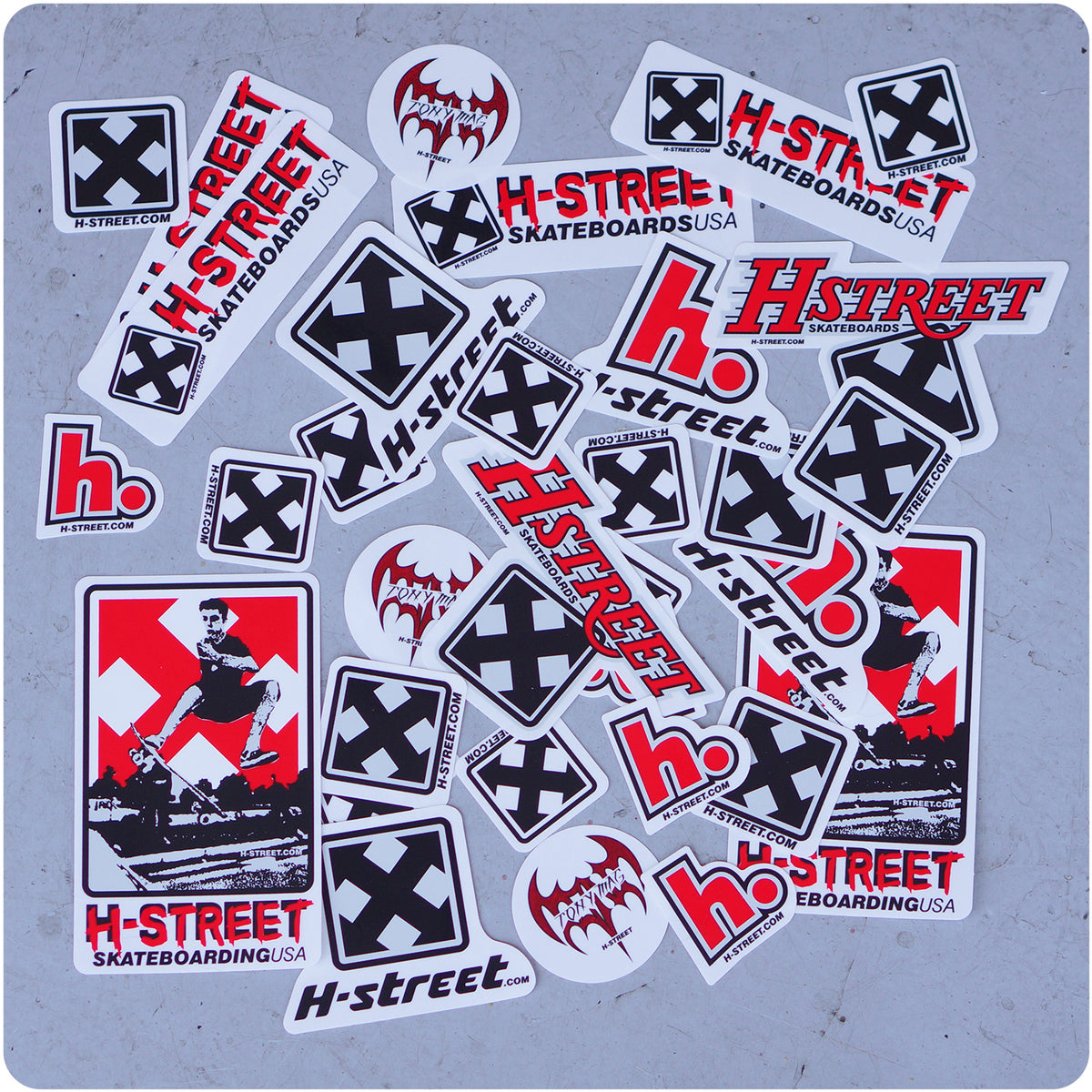 Stickers from the Inkgenda H-STREET 33 STICKER PACK, featuring H-Street logos, bold text, X symbols, and skateboarder images, are scattered on a gray surface—ideal for any Vans Combi pool fan.