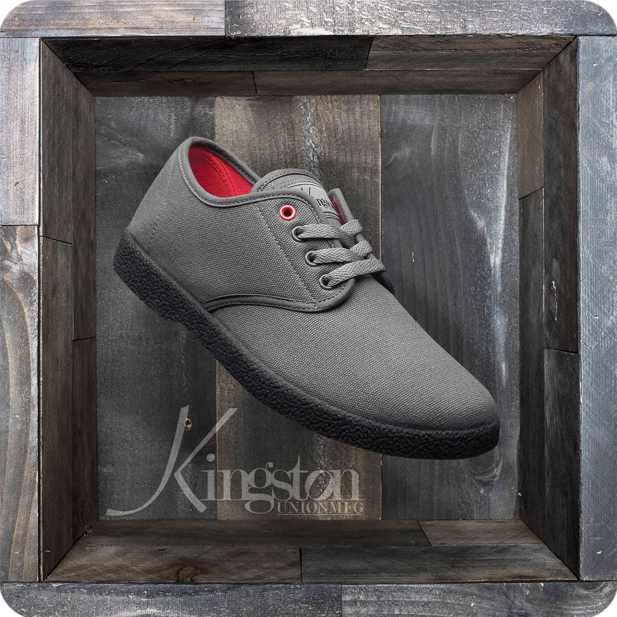 A gray KINGSTON UNION MFG WINO HENSLEY COLORWAY sneaker with black soles, red lining, gray laces, and a red eyelet sits in a rustic wooden shadow box. "Kingston Unionatic" is written on the background.
