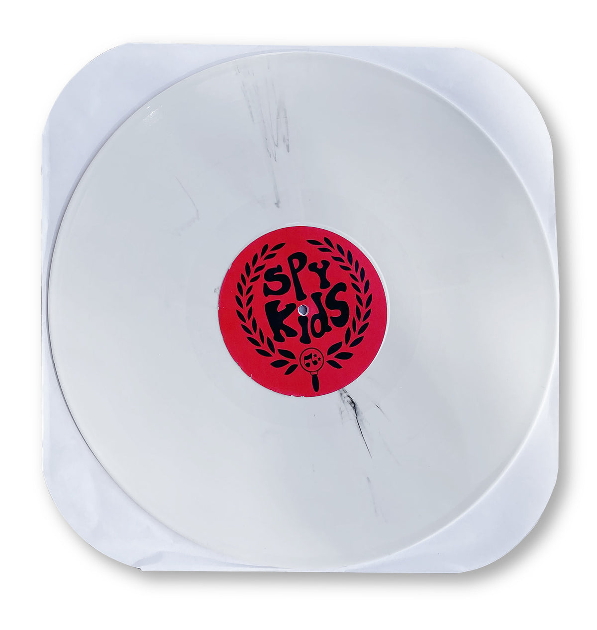 A translucent white SPY KIDS COVERT ACTION vinyl by Matt Hensley in a white paper sleeve, featuring a red center label with the band name in bold black letters, surrounded by a laurel wreath inspired by Jamaican music.