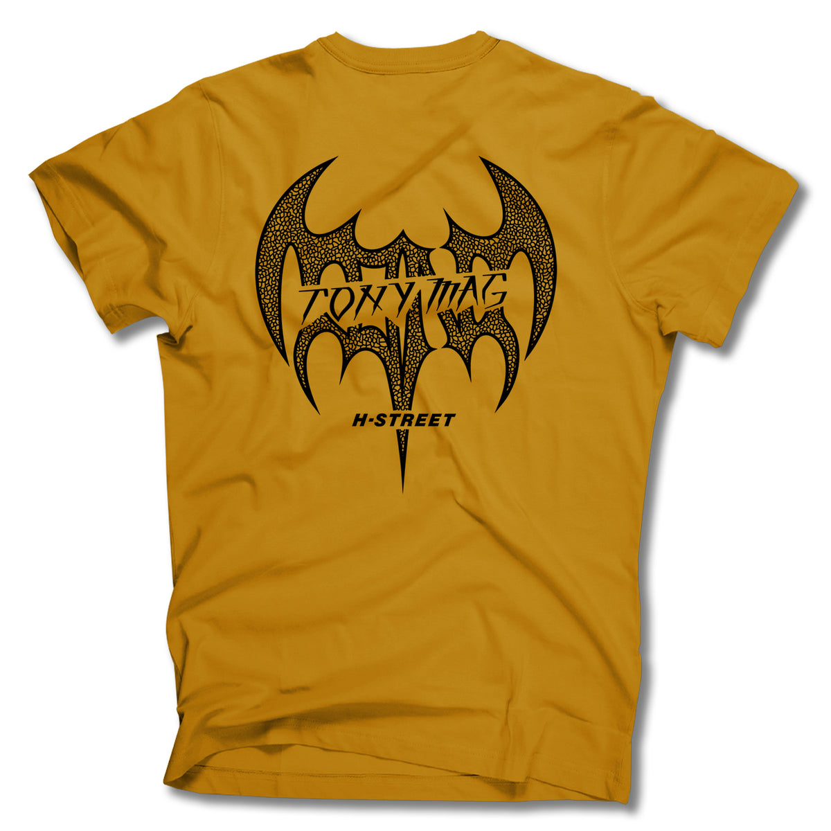 The Minuteman TONY MAGNUSSON BAT LOGO TEE is a mustard yellow shirt with a bold black bat-shaped graphic on the back, featuring TOXYMAG and H-STREET text, inspired by the classic Tony Mag Bat tee. Made in the USA.